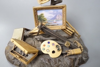 A 19th century Swiss gilt bronze, enamel, gem and paste mounted tableau of an artist's equipment, maker’s mark Malignon a Geneve, 11cm